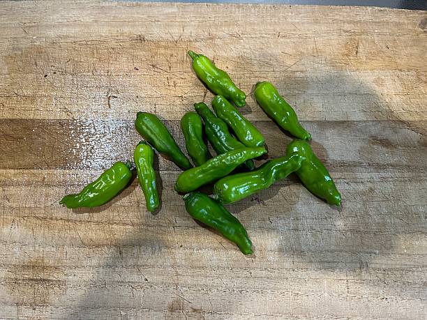 istock Small green pepper on the wooden cutting board 2240741633