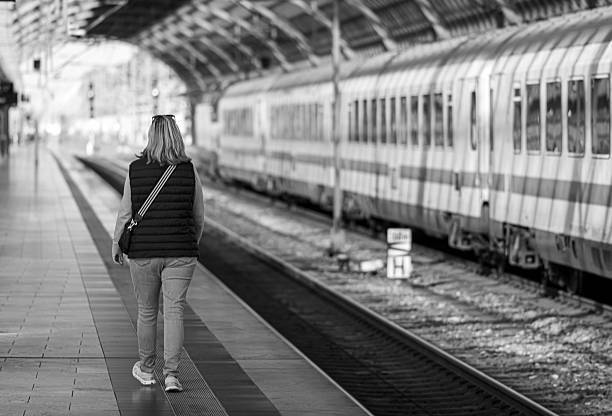 Germany, Berlin, railroad station Spandau, September 28, 2025 - Rear view of a woman on an empty platform next to a passenger train