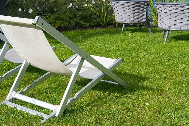 istock Empty lawn deck chair on grass lawn or park, relaxation on summer or spring sunny day. Hotel space, traveling and vacations on resorts. Garden furniture 2240743321