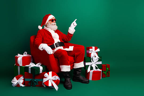 istock Festive Santa Claus Seated with Presents, Joyfully Matched with Sunglass Adding a Funky Twist to the Holiday Spirit 2240745808