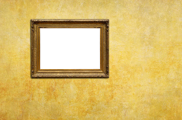 istock Ornate gold picture frame with blank white center mounted on textured yellow wall surface for art display and interior design mockup 2240746845