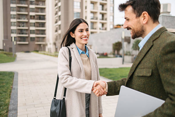 istock Smiling woman shaking hands outdoors in modern city area 2240749809