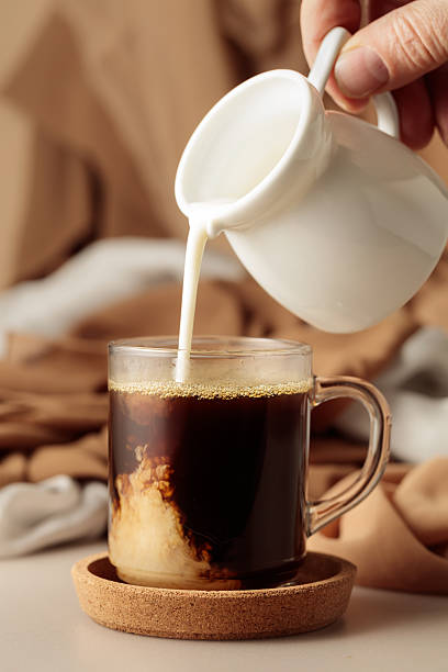 istock Pouring cream in black coffee. 2240750039