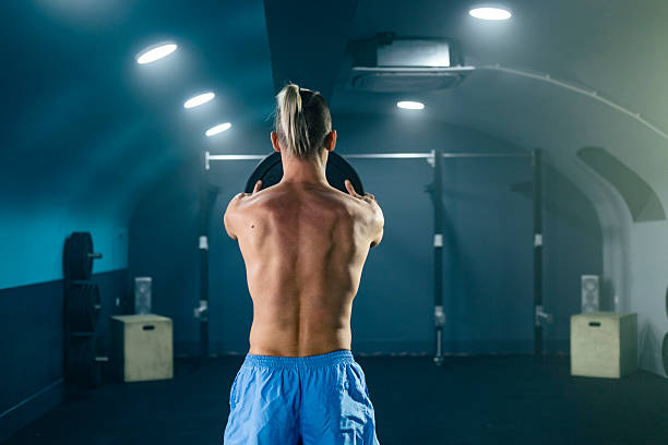 Strong man lifting weights in a gym, showing his back muscles