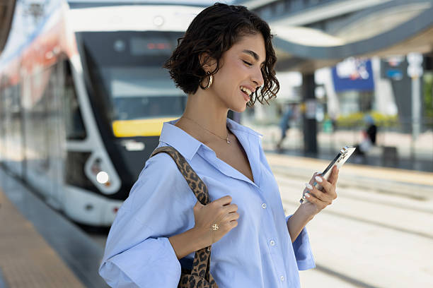 istock Woman using mobile phone at tram station 2240751852