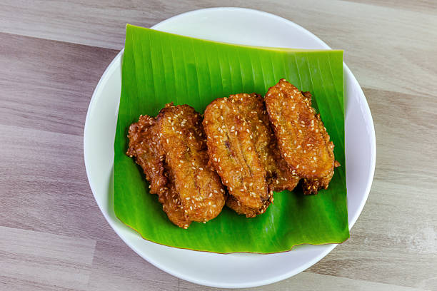 istock Crispy Thai fried bananas with sesame seeds served on a banana leaf in a white plate, Fried bananas is a traditional Asian snack with sweet, crunchy texture. Top view shot 2240753330