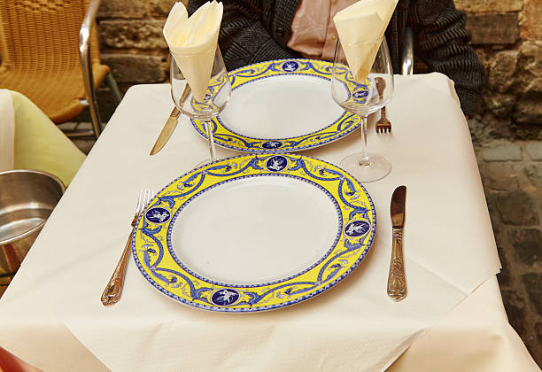 Elegant dining table set with decorative plates, cutlery, and glassware, featuring a charming outdoor ambiance, perfect for a romantic meal or special occasion with inviting atmosphere