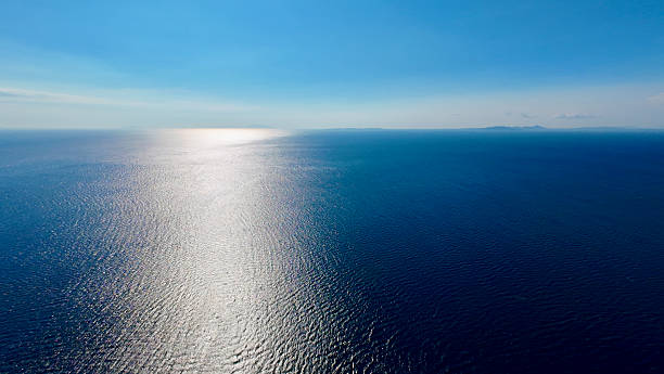 istock The calm ocean stretches endlessly under a bright blue sky as sunlight reflects on the water. 2240756655