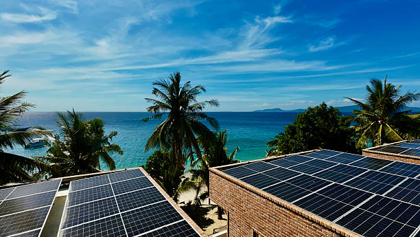 istock Solar panels on tropical resort rooftops overlook turquoise sea and palm trees. 2240756656