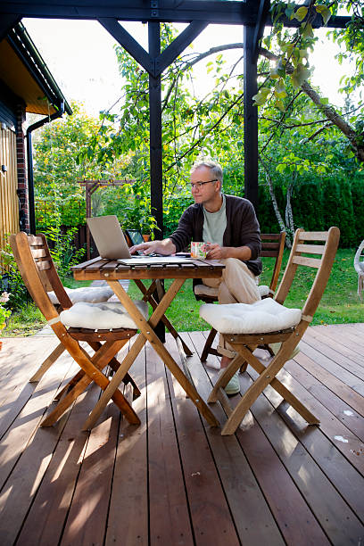 istock Middle aged man working remotely on laptop at cozy sunny patio, digital nomad lifestyle, outdoor home office, freelance and productivity concept 2240756780