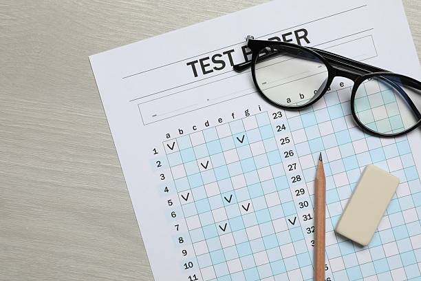 istock Answer sheet, eraser, pencil and glasses on wooden table, flat lay. Student passing exam 2240759879