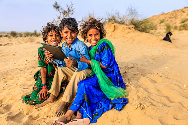 Group of happy Gypsy Indian children using digital tablet in desert village, Thar Desert, Rajasthan, India.