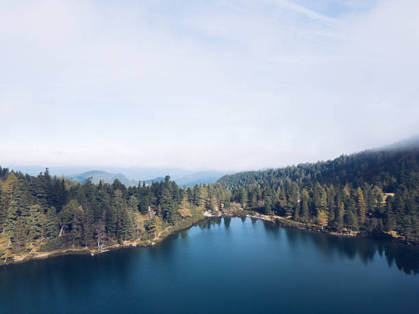 A tranquil mountain lake surrounded by alpine peaks and lush nature, reflecting the beauty of the Austrian Alps near Kleiner Scheibelsee on a clear day.