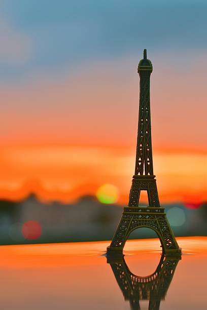 istock A miniature Eiffel Tower stands gracefully against a vibrant sunset sky, symbolizing dreams of travel and the charm of Parisian evenings 2240766312