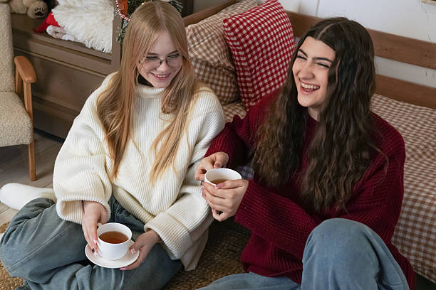 istock Two teenagers enjoying tea and laughter while sitting on a cozy rug in a warm setting 2240768685