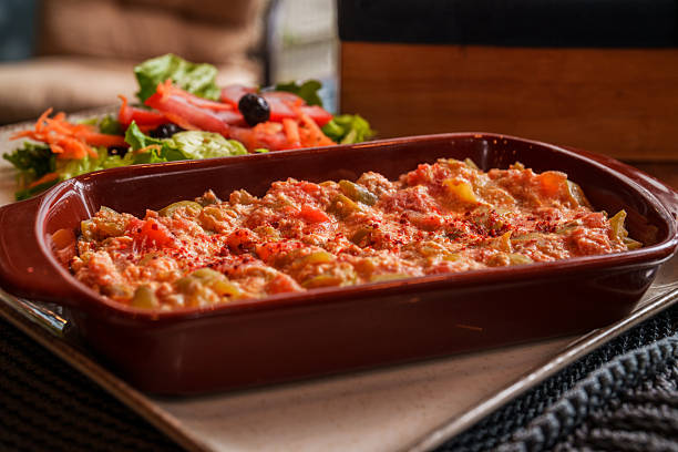 Close-up of a traditional Turkish menemen dish made with scrambled eggs, tomatoes, green peppers, and spices, served in a rustic casserole alongside a fresh vegetable salad.