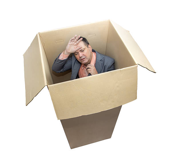 istock Stressed man in a suit standing inside a cardboard box, isolated on white background 2240770833