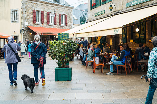 Shoppers and cafe visitors on Rue Saint Guenole in the town of Concarneau in the Brittany region of France.