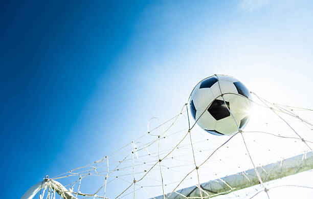 istock Soccer ball hitting the goal net against blue sky background 2240776408