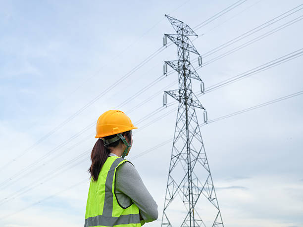 istock Electrical Technician Inspects High Voltage Power Lines Amid Clear Sky in Safety Gear for Electrical Utility Maintenance and Management Work Environment 2240776684