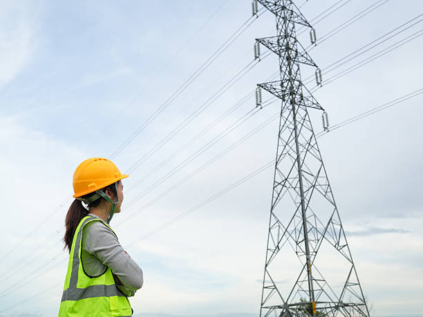 istock Worker in hard hat and safety vest observes a high voltage power line under a cloudy sky, emphasizing safety in industrial environments and energy infrastructure 2240776691