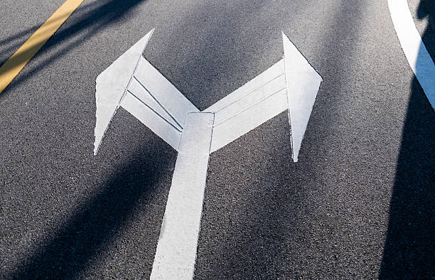 Two directional arrow symbol on asphalt road with shadow