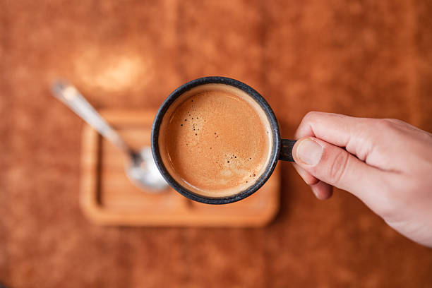 istock Hand Holding Coffee Mug Above Wooden Tray 2240778213