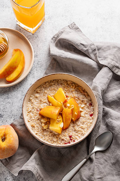 istock Oatmeal with peaches and nuts  in a bowl on a light background with honey, 2240781277