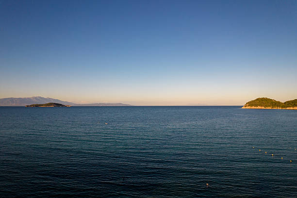 Ocean water stretching to the horizon with two distant islands under a clear blue sky