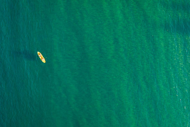 A bright yellow rented kayak glides across the blue ocean off the coast of Kailua, Hawaii, with the expansive sky overhead adding to the sense of adventure.