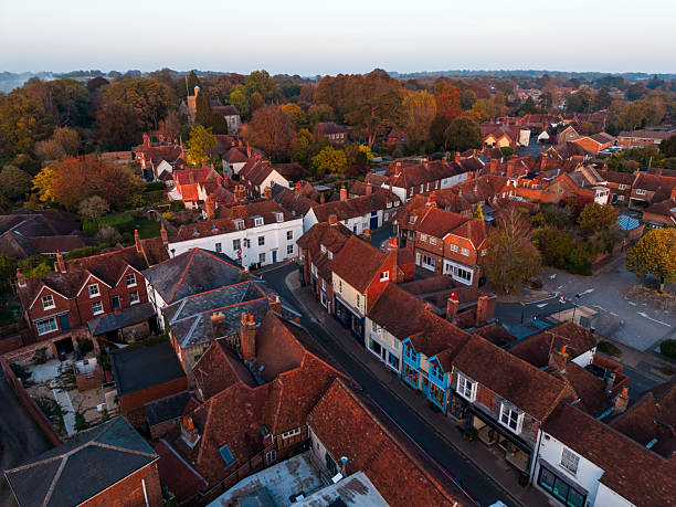 Aerial view showing charming english village houses, historic church, and vibrant autumn trees under the warm evening light