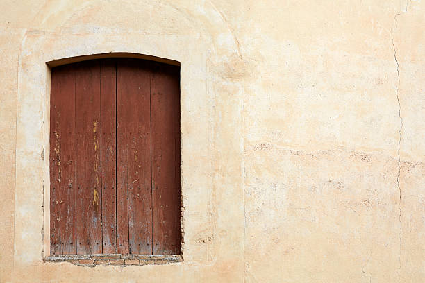 istock Old Rustic Wooden Door on Weathered Stucco Wall 2240790519