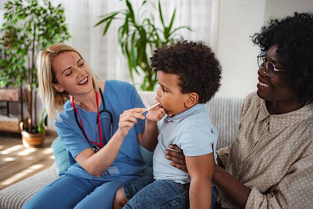 istock Pediatric nurse checking child's throat during home visit 2240792296