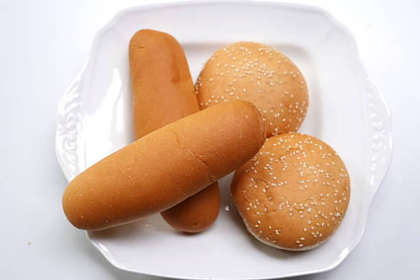 Fresh burger bun and hot dog bun served on white dish.