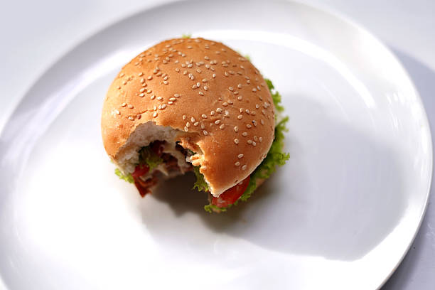 Burger of sesame buns, lettuce and cutlets with tomato sauce decorated with a skewer. fast food for a children's party.