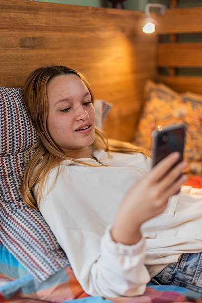 istock Teenager relaxing in bed while looking at her phone Vertical 2240797018
