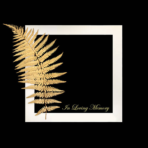 In loving memory gold fern leaf design tribute for remembrance card on black background, white frame. Floral design for funeral with text.