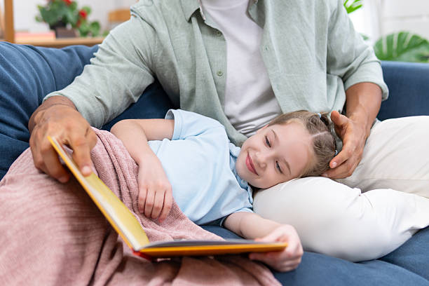 istock Dad Reading to Mixed-Race Daughter on the Sofa 2240804275