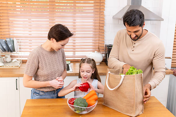 istock Latin Dad, White Mom & Mixed-Race Daughter Sorting Groceries in Cozy Kitchen 2240804362