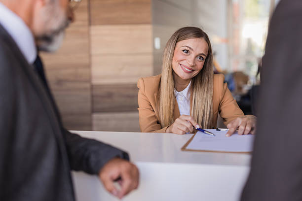 istock Smiling receptionist helping businessmen at hotel check-in 2240808220