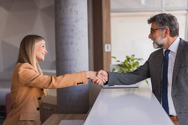 istock Businessman and receptionist shaking hands at reception desk 2240808261