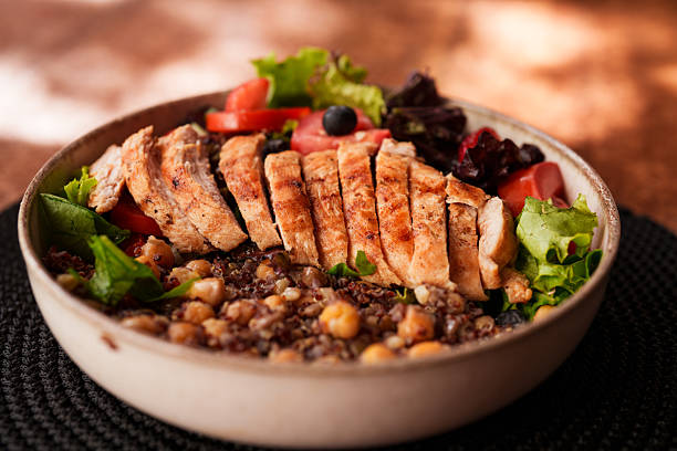 A protein-packed bowl featuring tender grilled chicken breast served over a hearty mix of lentils, chickpeas, and fresh greens. Topped with seasonal fruits and a light dressing, combining nutrition and flavor in perfect balance.