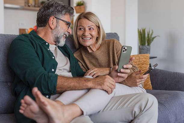istock Mature couple relaxing on sofa using smartphones together 2240811650