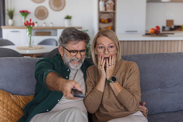istock Mature couple reacting with shock while watching tv 2240811661