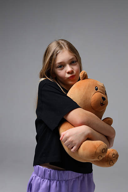 istock Young caucasian girl holding teddy bear and posing in studio 2240812402