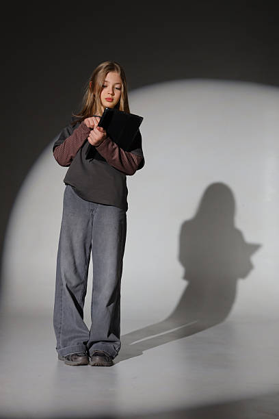 istock Caucasian female child in casual outfit using digital tablet in studio lighting 2240813239
