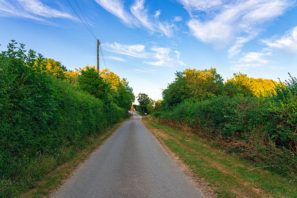 Empty country road leading through fields at sunset in england