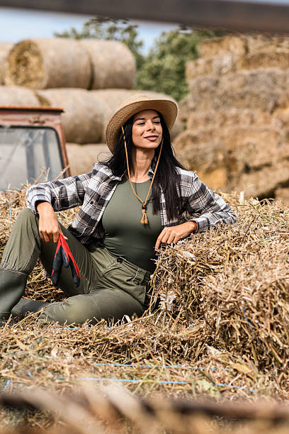 istock Proud Young Female Farmer Resting on Hay Bales 2240823563