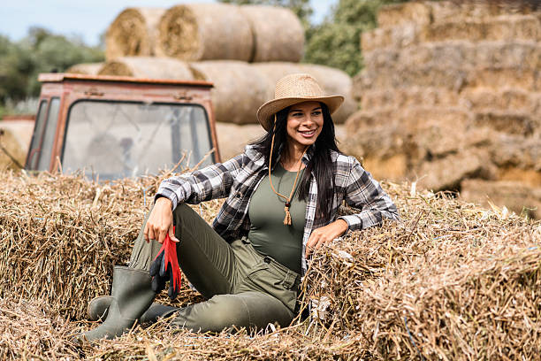 istock Smiling Female Farmer Sitting on Hay Bales 2240823581