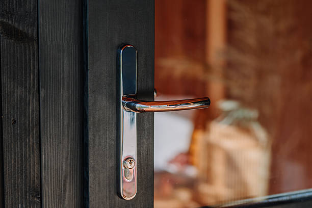 istock Modern chrome door handle on a dark wooden door with glass panel reflecting warm interior decor, natural wood textures, and soft lighting. 2240825218